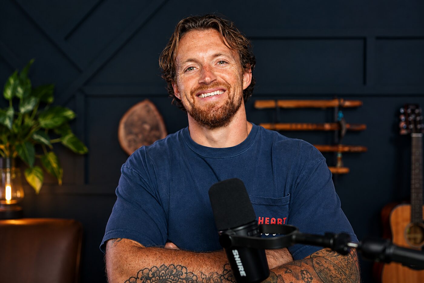 Ste at the microphone in his podcast studio, arms folded, smiling